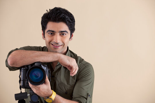Handsome young man with digital camera over colored background 