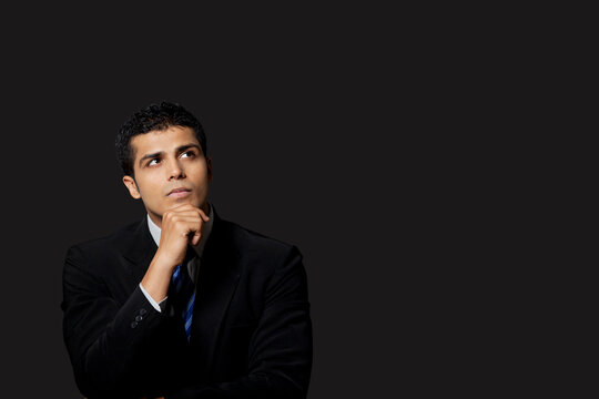 Handsome businessman looking away over black background 