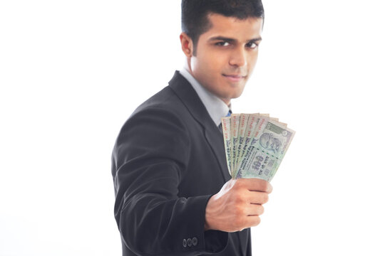 Handsome business man holding Indian currency over white background 