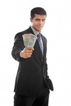 Confident businessman holding Indian currency over white background 