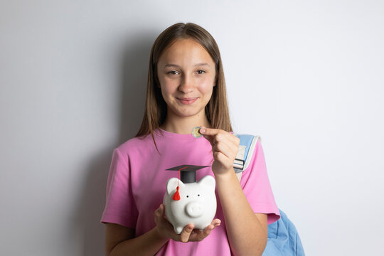 Teenage girl with backpack holding a piggy bank with graduation cap, concept of saving money for education