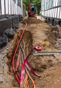 Underground Utility Construction in Narrow Historic Street with Excavator and Exposed Cables