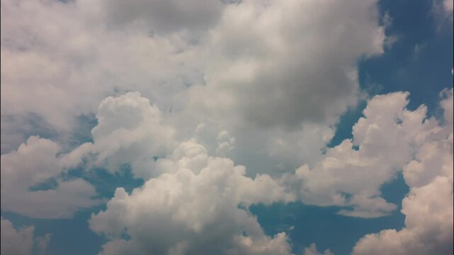 White puffy clouds drifting across a bright blue sky during a sunny afternoon capturing nature in motion