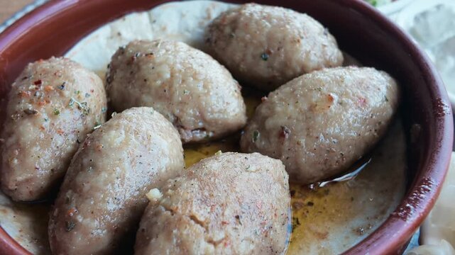 Traditional Kibbeh Served in a Clay Dish with Side Dishes