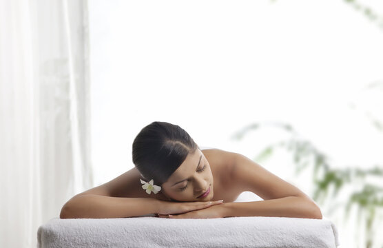 Pretty woman with eyes closed lying on message table 