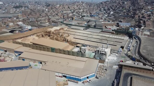 Aerial view of an industrial area surrounded by crowded favelas in san martin de porres, lima, peru