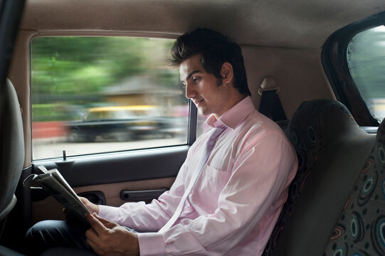 Businessman reading a newspaper in a car 