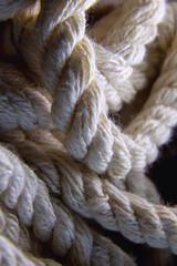 Vertical close-up of a natural twisted cotton rope illuminated by dramatic light. © Александр Ланевский