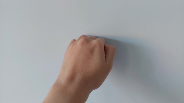 Closeup of a hand repeatedly knocking on plain, clean wall surface, illustrating home inspection, building material quality control, construction, renovation, communication, tapping, and body gesture.