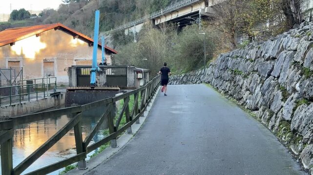 Young athletic man running on a riverside path