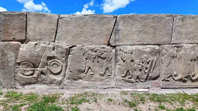 Ancient Hittite orthostat relief wall depicting a chariot wheel, lute players, and acrobats at the Alacah&ouml;y&uuml;k archaeological site, Turkey.
