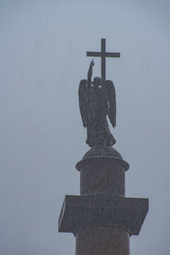 Silhouette of angel with cross on top of Alexander Column under grey sky