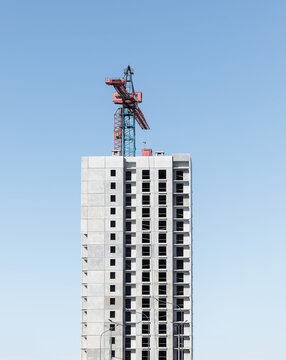 High-rise panel building under construction beside a tower crane. Multistory residential structure
