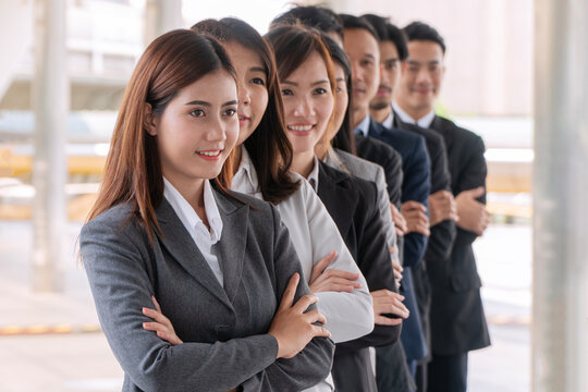 Portrait of a confident Asian business team standing in a row with arms crossed outdoors in the city. Successful corporate professionals, leadership, and teamwork concept.