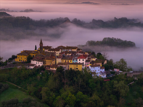 Aerial view of the historic village of Piantravigne nestled in the rolling hills of Tuscany, surrounded by thick morning mist under a soft golden sky in Piantravigne, Tuscany, Italy.