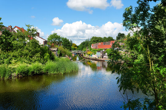 Friedrichstadt, Germany - Scenic canal lined with trees and historic houses. The peaceful canal with historic houses reflects the unique charm of Friedrichstadt,