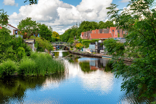 Friedrichstadt, Germany - Scenic canal lined with trees and historic houses. The peaceful canal with historic houses reflects the unique charm of Friedrichstadt,