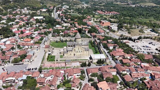 Cinematic drone orbit over Svetitskhoveli Cathedral and ancient Mtskheta, Georgia, showing the UNESCO landmark, medieval stone architecture and surrounding historic town from another aerial angle