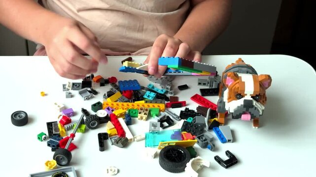 A child plays with colorful building blocks at a desk near a built toy dog, creative child leisure, educational toy concept, home activity.