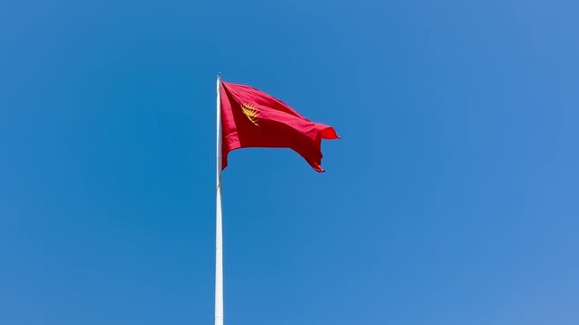 The red and yellow flag of Kyrgyzstan in the blue sky