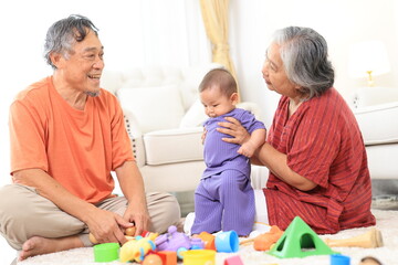 Obraz premium Asian family grandmother, grandfather ,son playing with colorful kid toys. Happy baby boy in kindergarten or daycare. Child playing with colorful educational toys at home. Asian woman. Happy family.