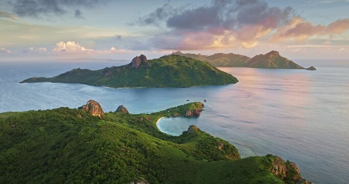 Aerial view of lush green islands surrounded by the blue ocean with rocky outcrops and soft sunset light, Savusavu, Northern Division, Fiji.