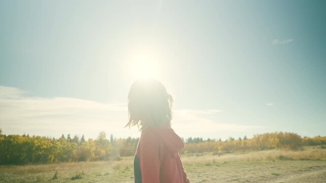 Boy hauling a branch through autumn forest with golden lens flare through trees