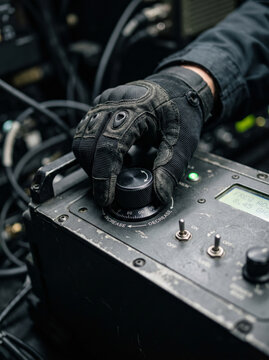 Gloved hand operating switches on military electronic communications control panel interface