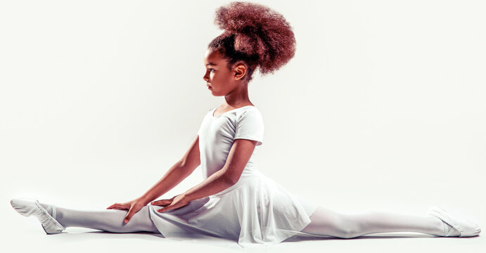Ballerina in dance class. Kids practice full split. Little ballerina girl laying on the ground