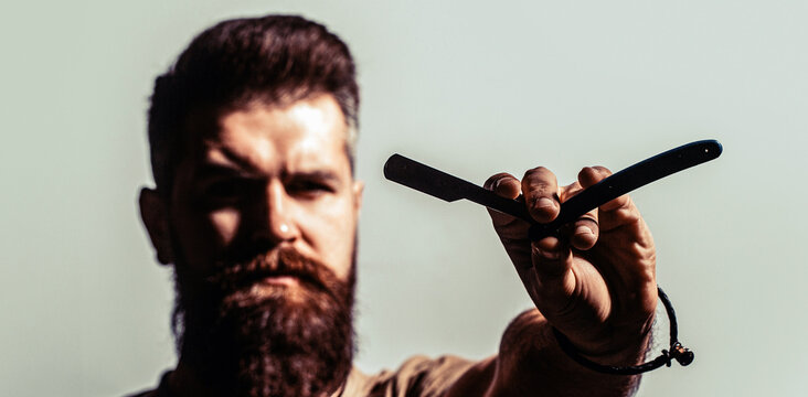 Blade for razor. Barbershop service concept. Vintage straight razor. Handsome bearded holding a straight razor while standing at the barbershop