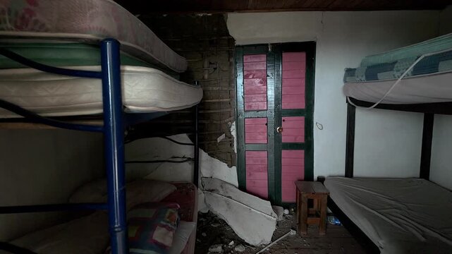 interior view of damaged bedroom after earthquake with collapsed wall and bunk beds