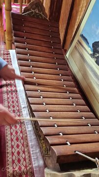 Person playing wooden xylophone with mallets, musical performance, ethnic instrument showcase, cultural music experience.