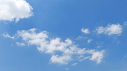 Fototapeta premium Clear blue sky with bright white fluffy clouds on a beautiful sunny day. Natural scenery background with blue sky and beautiful white clouds.