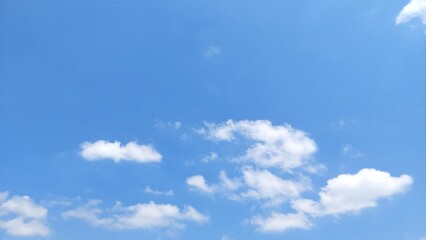 Fototapeta premium Beautiful clear blue sky with fluffy white clouds on a bright sunny day. Natural sky scenery with bright white clouds and blue sky background.