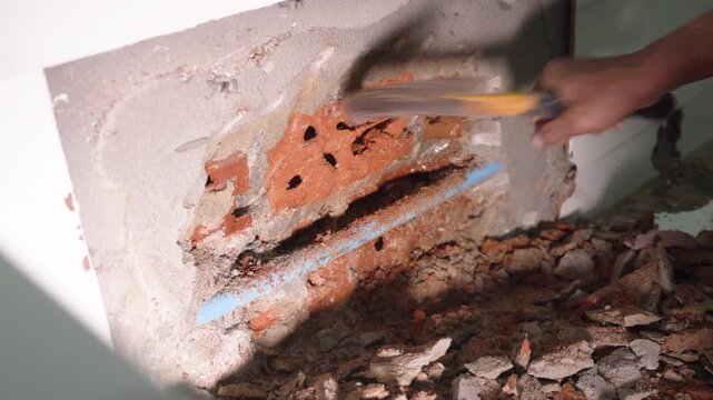 Exposed plumbing pipe inside a cracked wall reveals hidden home maintenance problems, water leakage, moisture damage, corrosion, renovation work, and the need for professional repair.