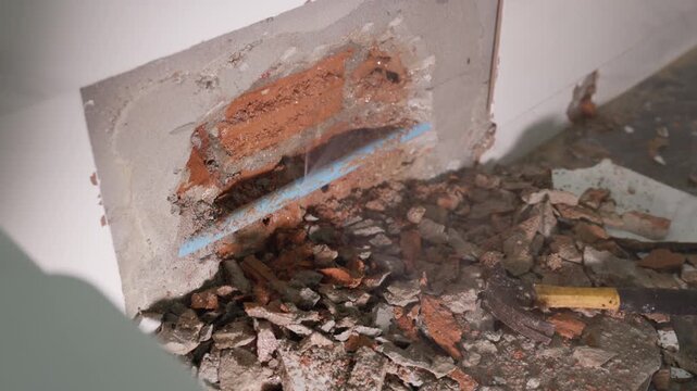 Exposed plumbing pipe inside a cracked wall reveals hidden home maintenance problems, water leakage, moisture damage, corrosion, renovation work, and the need for professional repair.