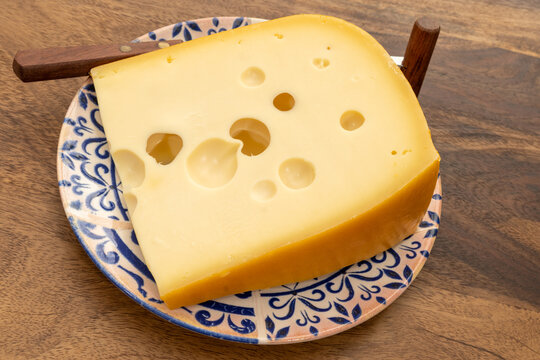 French Emmental cheese from Savoie Alps with large holes, traditional fermentation and aging, pale golden color, firm creamy texture, French food