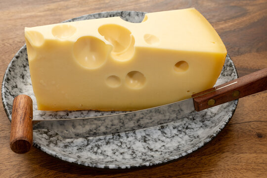 French Emmental cheese from Savoie Alps with large holes, traditional fermentation and aging, pale golden color, firm creamy texture, French food
