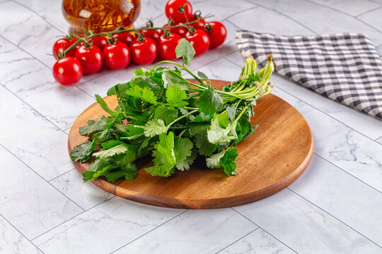 Fresh cilantro on wooden cutting board with cherry tomatoes and olive oil