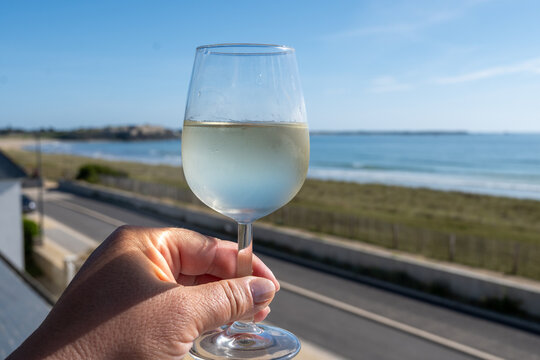 Chilled glass of dry French white wine with ocean view and coastal horizon. Elegant wine tasting on French seaside at summer
