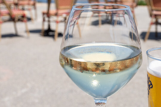 Chilled glass of dry French white wine with ocean view and coastal horizon. Elegant wine tasting on French seaside at summer
