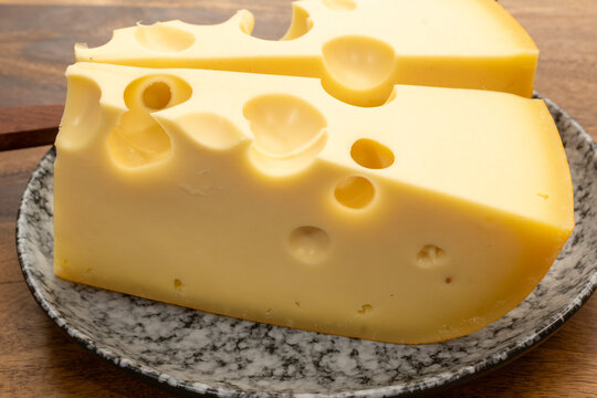 French Emmental cheese from Savoie Alps with large holes, traditional fermentation and aging, pale golden color, firm creamy texture, French food