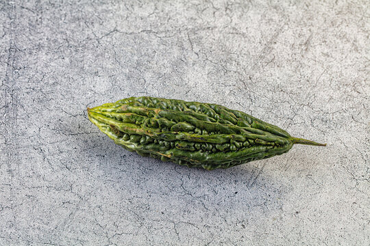 Green bitter melon on textured gray surface