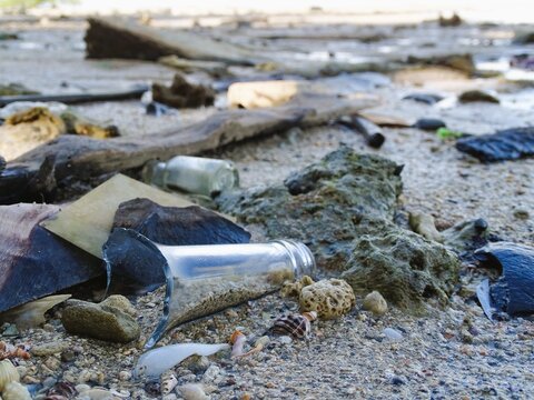 Shards of glass bottles lay scattered on the beach sand.
