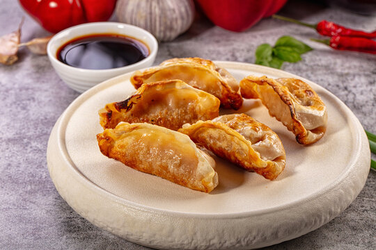 Crispy golden dumplings on ceramic plate with soy sauce and fresh ingredients