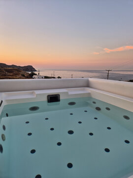 Serene sunset view from a hot tub overlooking the coast of Milos, Greece
