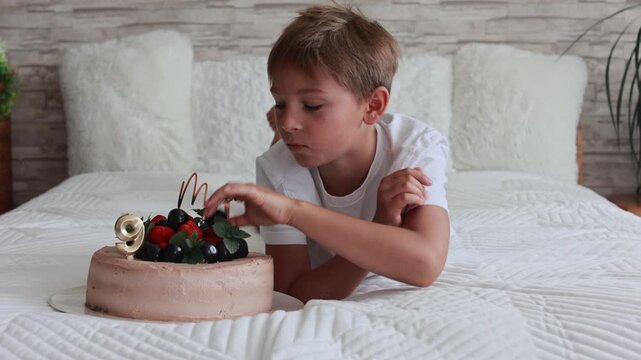 Cute preschool boy with birthday cake with candles at home, preparing for party with friends and siblings