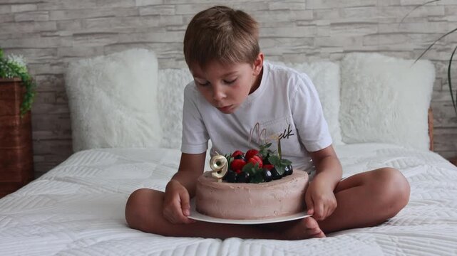 Cute preschool boy with birthday cake with candles at home, preparing for party with friends and siblings
