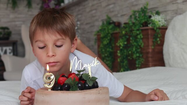 Cute preschool boy with birthday cake with candles at home, preparing for party with friends and siblings