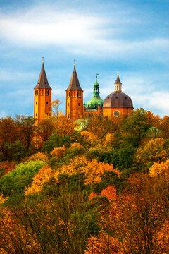 Historical Plock Cathedral on Tumskie Hill surrounded by colorful autumn forest foliage. Plock, Poland